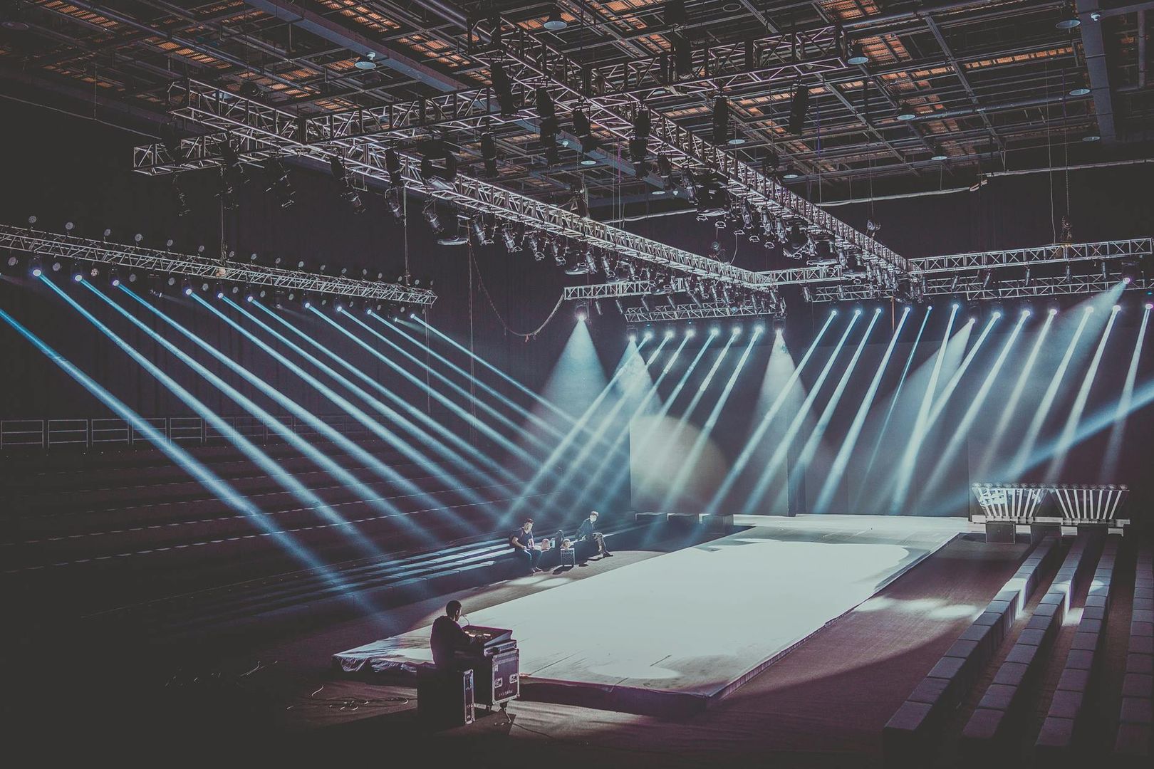 Scene med blå lysstråler, catwalk og teknisk utstyr, klar for en forestilling.